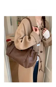 Close-up of vintage brown tote bag featuring drawstring detail and lychee grain leather