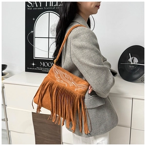 Close-up of brown suede bag with bohemian embroidery and long decorative tassels