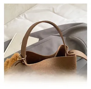 Detailed shot of brown litchi grain leather bucket bag with a cute plush bear charm