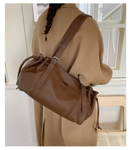 Brown lychee leather tote bag featuring drawstring detail and adjustable metal grommet strap