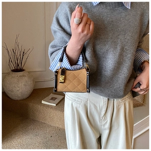 Close-up of a camel suede mini bag with diamond quilting and gold twist lock