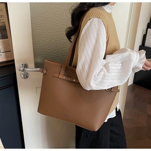 Sac cabas en cuir marron grainé porté par un mannequin dans un intérieur élégant