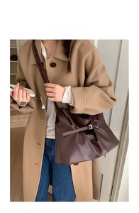 Detailed view of dark brown leather shoulder bag with elegant pleats and metal buckle strap