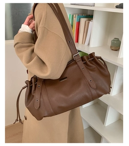 Detail of dark brown lychee leather shoulder bag with drawstring and silver hardware