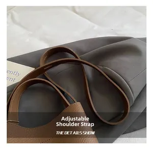 Detail view of adjustable leather shoulder strap on a brown bucket bag with lychee texture