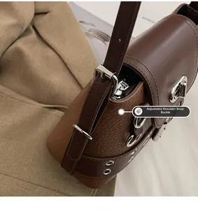 Gros plan sur la boucle argentée et le cuir grainé marron de ce sac à bandoulière chic