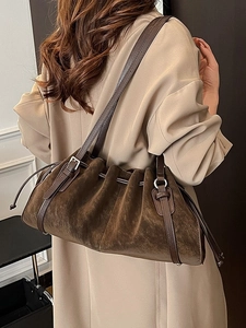 Vintage dark brown suede shoulder bag with pleated drawstring design worn with a trench coat