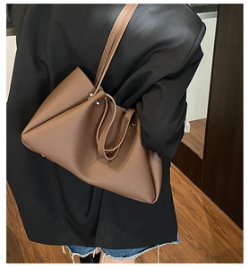 Detail shot of a large brown leather tote bag with a rich lychee grain texture for commuting