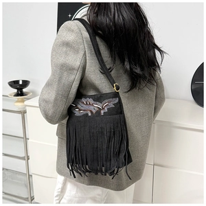 Detail of embroidered pattern and long fringe on black suede bucket bag for women