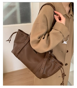 Detail of dark brown lychee grain leather tote bag with drawstring and metal eyelets