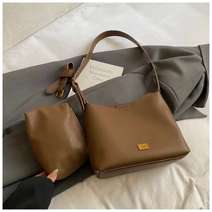 Détail de l'ensemble sac seau en cuir marron foncé avec logo carré doré et texture