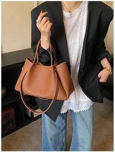 Macro detail of caramel brown pebble leather tote bag with silver rivets and shoulder strap