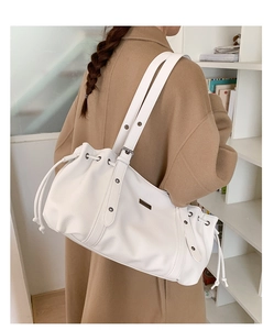 Close-up of a white lychee grain leather drawstring shoulder bag on a female model