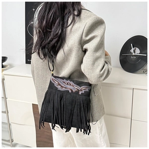 Close-up of black fringe crossbody bag with embroidery detail and chic tassel accents