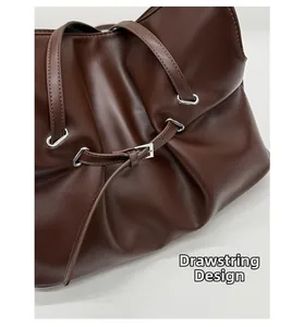 Close-up of deep brown leather bag showing soft pleats and drawstring closure with metal buckle
