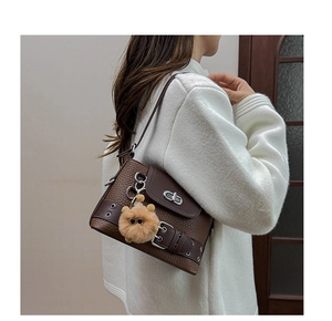 Détail du sac baguette marron avec fermoir métallique et breloque ours en peluche
