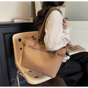 Gros plan sur un sac cabas en cuir marron avec sangles à rivets et boucle métallique