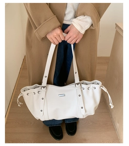 Detail of white leather tote bag featuring lychee texture and drawstring closure
