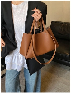 Detail of brown lychee grain leather tote bag with elegant folds and shoulder strap