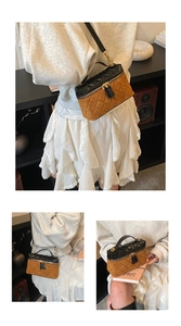 Detail view of contrast color quilted box bag with dual zippers and leather strap