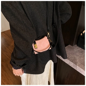 Detail of pink quilted crossbody bag with black trim and gold-tone metal hardware