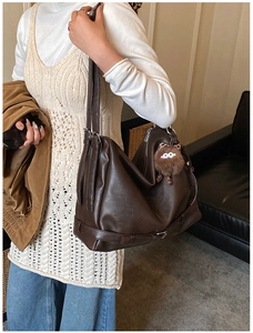 Detail of dark brown tote bag featuring soft PU leather texture and plush monster charm