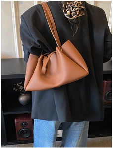 Brown lychee texture leather tote bag worn by a model in a minimalist indoor setting