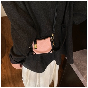 Detail of pink quilted mini crossbody bag featuring a gold square lock and black trim