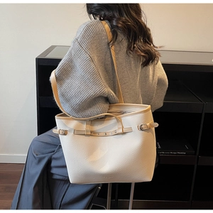 Détail d'un grand sac cabas crème avec anses marron porté par un mannequin chic