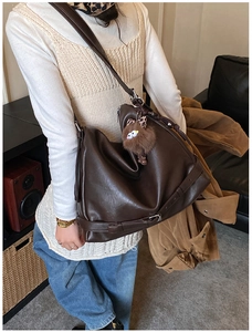 Detail view of large brown shoulder bag in oiled leather with cute plush animal charm
