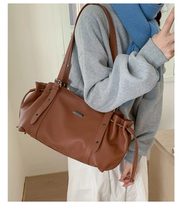 Detail view of caramel brown leather tote bag with stylish drawstring pleated side design