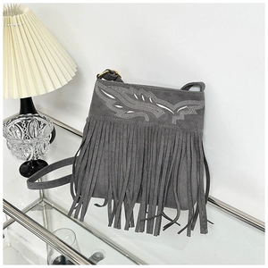 Detail of grey frosted crossbody bag featuring fringe tassels and wing embroidery accents
