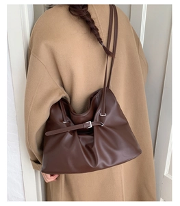 Detail of dark brown leather tote bag with pleated texture and stylish metal buckle