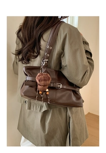 Detail of dark brown vintage shoulder bag with plaid hat charm on trench coat