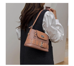 Détail du sac en cuir rose texturé avec œillets métalliques et boucle sur la bandoulière