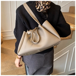 Detail of taupe pebbled leather tote bag with dual straps and metal bottom studs