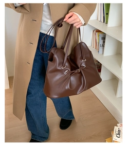 Detail of dark brown leather tote bag with elegant pleated design and silver hardware