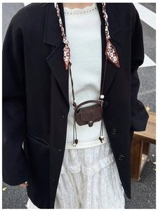 Detail of vintage brown mini crossbody bag with beaded cord strap on a black blazer