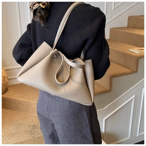 Greige pebbled leather tote bag with elegant pleated design shown on a model