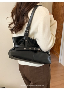Detail of black retro shoulder bag with metallic eyelet straps and glossy finish