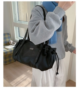Close-up of black lychee grain tote bag featuring drawstring detail and metal eyelets