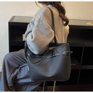 Gros plan d'un sac cabas noir en cuir grainé avec fines bandoulières porté par un mannequin