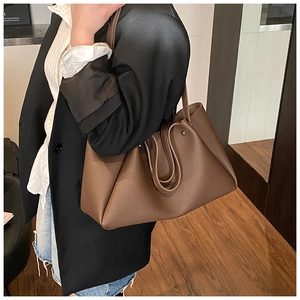 Detail of dark brown tote bag in pebbled leather texture worn with a blazer
