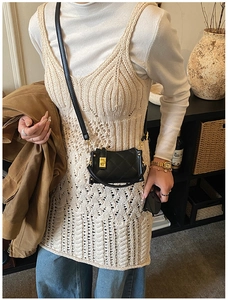 Detail of a black quilted crossbody bag with gold-tone twist lock on a knit outfit