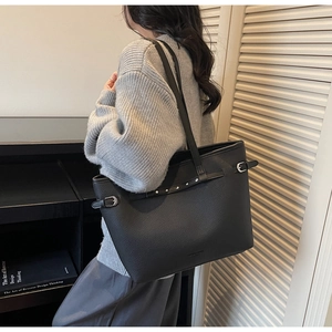 Détail d'un grand sac cabas en cuir noir texturé avec boucle de réglage latérale