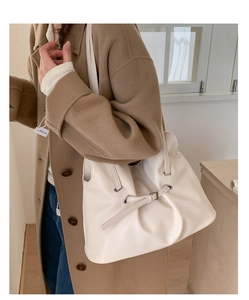 Detail of a minimalist beige pleated tote bag with drawstring and silver buckle hardware