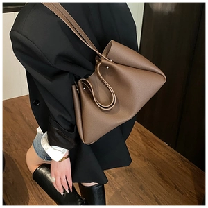 Detail of dark brown leather tote bag with lychee grain texture on a model