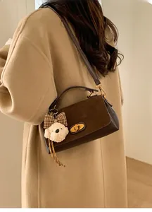 Detail view of brown shoulder bag with gold twist lock and cute teddy bear charm
