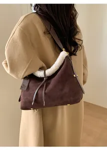 Detail of dark brown suede shoulder bag with white faux fur trim and gold hardware