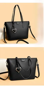 Close-up of black lychee grain leather tote bag with heart charm and brand embossing